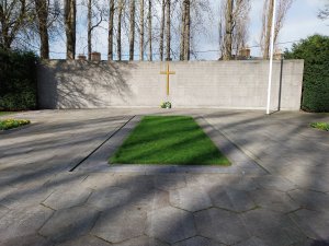 Hexagonal paving leading to curved memorial wall with a gold cross in the center