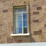 Close up of a window surrounded by dark red and pale orange-yellow sandstone